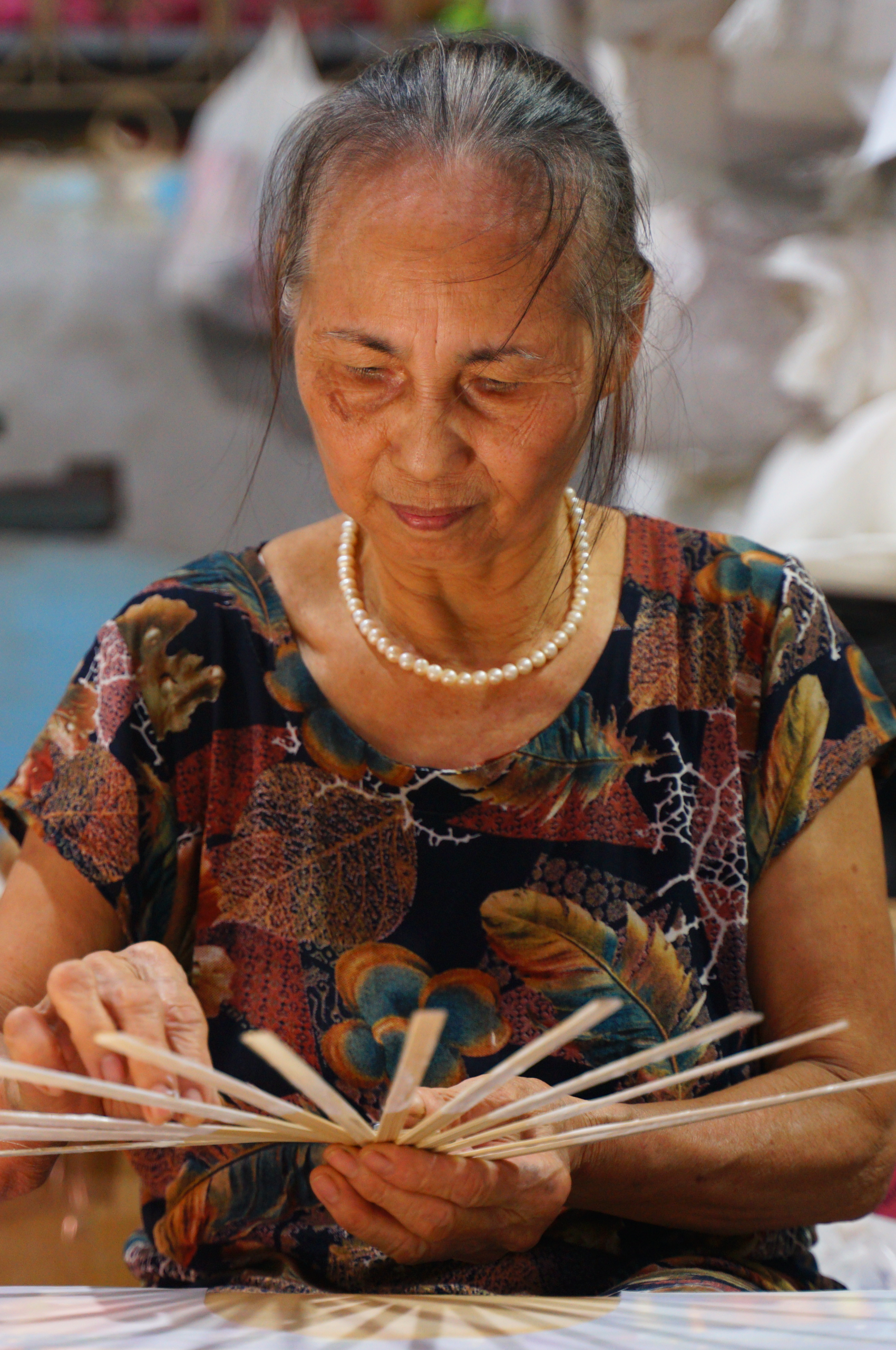Nghệ nhân Bà Mai đang vẽ họa tiết trên quạt giấy thủ công